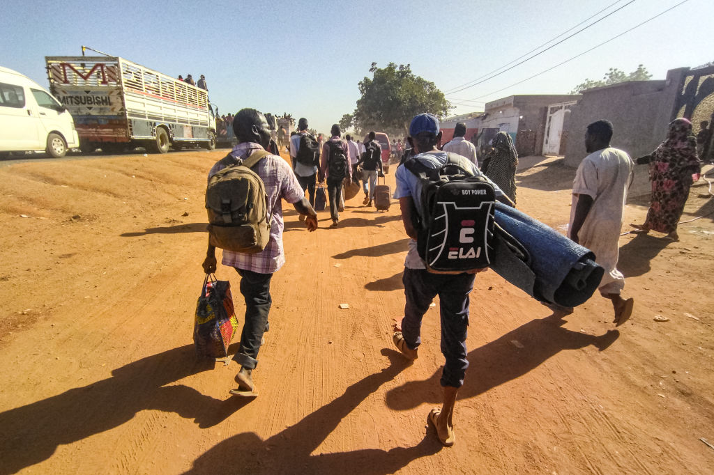 مواطنون سودانيون يحملون حاجياتهم وهم في طريق النزوح من مدينة ود مدني بولاية الجزيرة