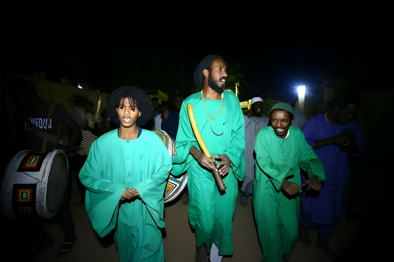 ثلاثة أشخاص يرتدون الجلباب الأخضر في شهر رمضان في فعالية النوبة التي تعتبر من عادات وتقاليد الصوفية في السودان