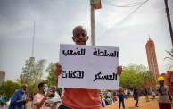 متظاهر يحمل لافتة مكتوب عليها "السلطة للشعب والعسكر للثكنات"