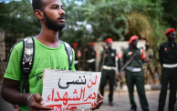 شاب يحمل لافتة عليها "لن ننسى دم الشهداء" 