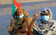 امرأتان في مظاهرة تحمل إحداهن علم السودان