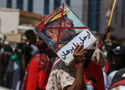 شاب يرفع لافتة "ارحل يا برهان" في احتجاجات في السوجان