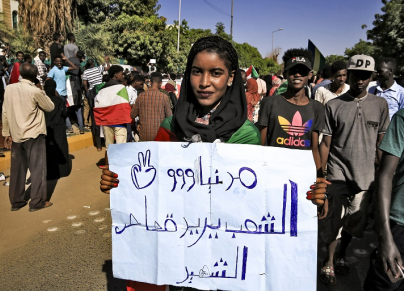 متظاهرة سودانية تحمل لافتة تطالب بقصاص الشهيد