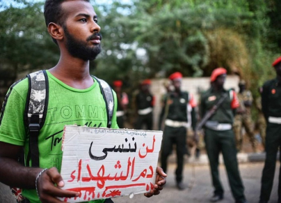 شاب يحمل لافتة عليها "لن ننسى دم الشهداء" 