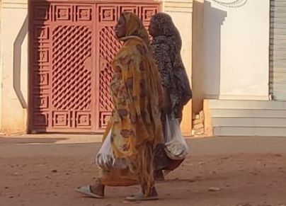 سيدتان من السودان تحملان مواد غذائية في الحرب