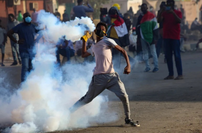 شاب يعيد عبوة غاز مسيل للدموع إلى القوات الأمنية في مظاهرة رافضة للحكم العسكري في السودان