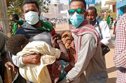 شابان يحملان مصابًا في مظاهرات في الخرطوم
