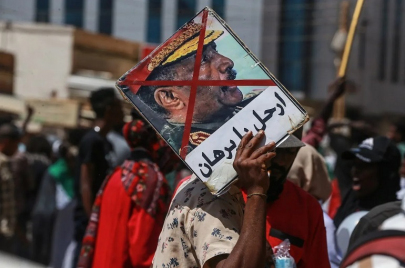 شاب يرفع لافتة "ارحل يا برهان" في احتجاجات في السوجان