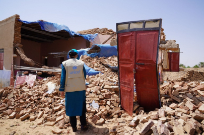 مسؤول أممي أمام منزل هدمته السيول والأمطار في السودان