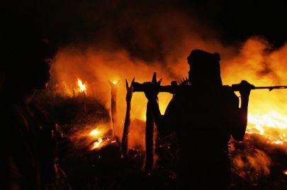 رجل مسلح يقف أمام نار مشتعلة في السودان