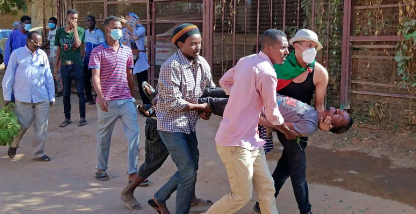 محتجون يسعفون مصابًا في مظاهرة بالخرطوم
