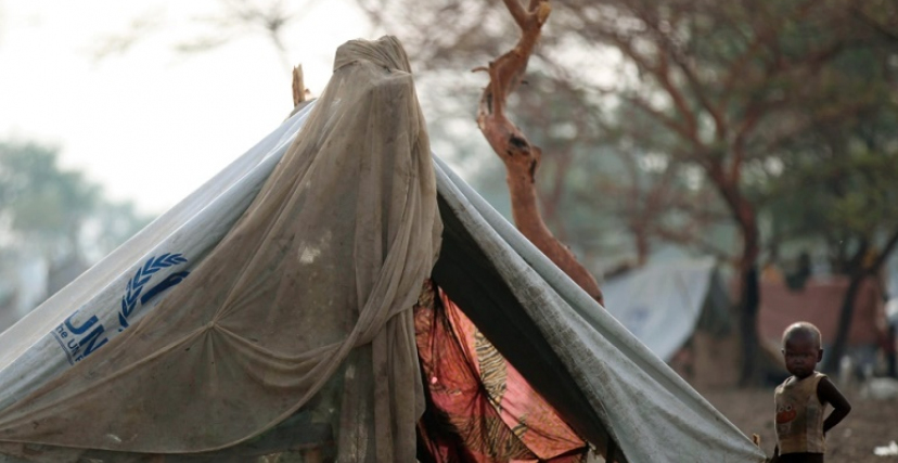 طفل يجوار خيمة بها شعار للأمم المتحدة