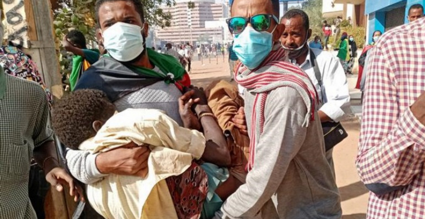 شابان يحملان مصابًا في مظاهرات في الخرطوم