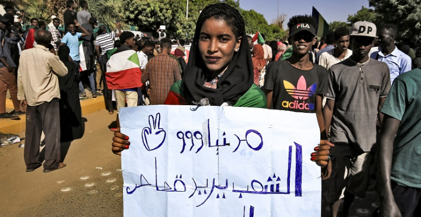 متظاهرة سودانية تحمل لافتة تطالب بقصاص الشهيد