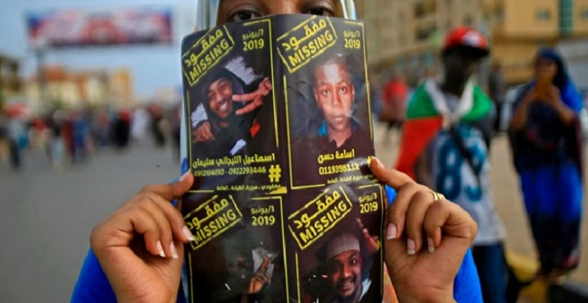 شابة تحمل صورة مفقودين في العاصمة الخرطوم