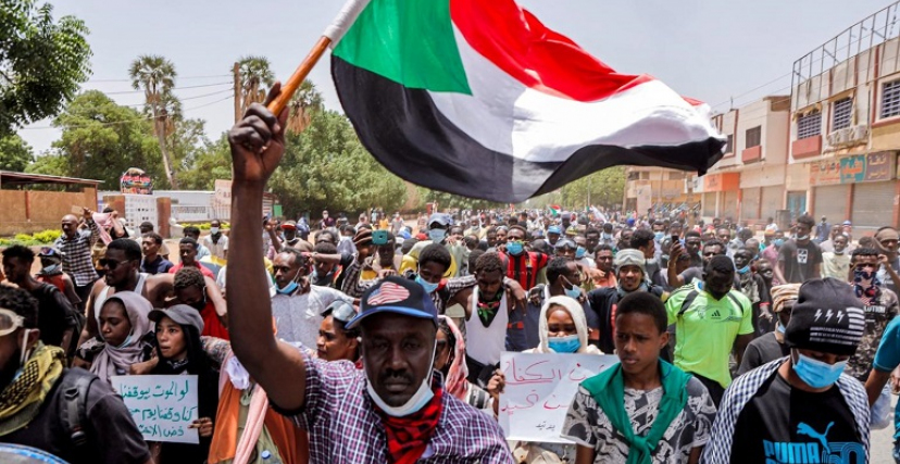 رجل يحمل علم السودان في مظاهرة رافضة للحكم العسكري