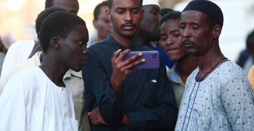 شباب سودانيون يتحلقون حول هاتف بيد أحدهم