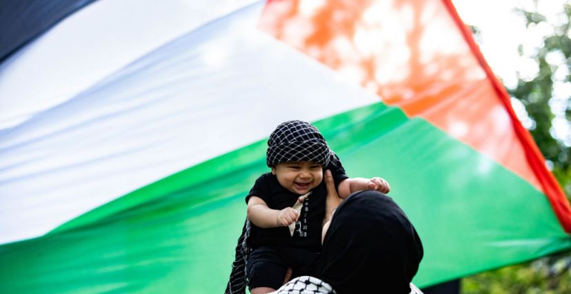 سيدة تحمل طفلًا - كوفية - علم فلسطين