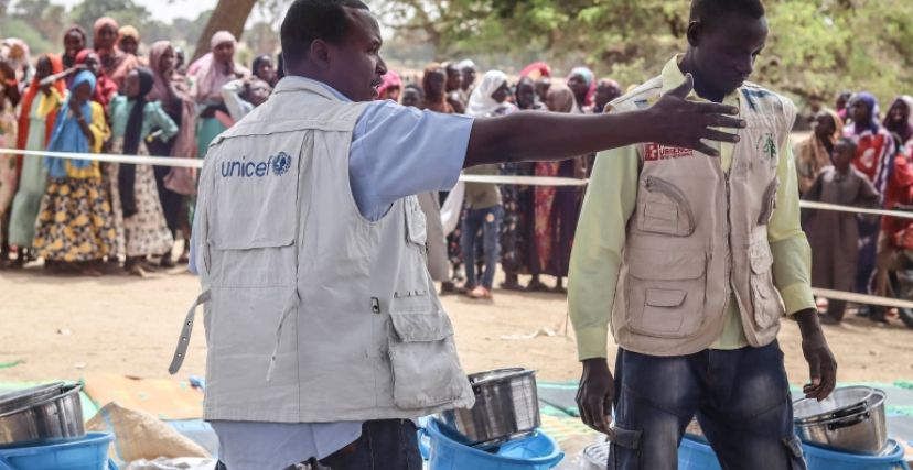 عاملون في الأمم المتحدة يوزعون مساعدات إنسانية على لاجئين سودانيين