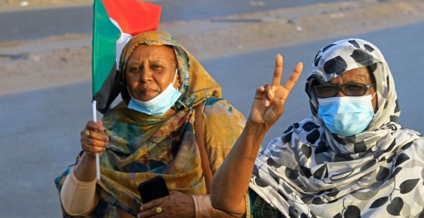 امرأتان في مظاهرة تحمل إحداهن علم السودان