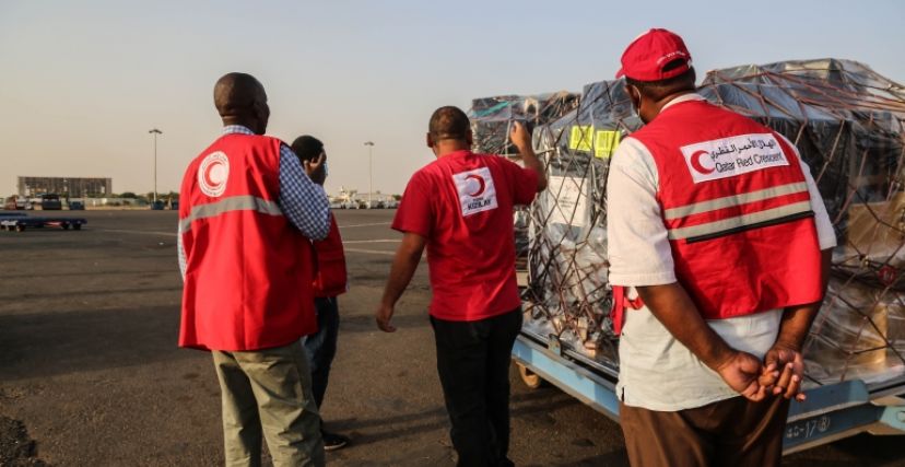 عاملون في الهلال الأحمر القطري يستلمون مساعدات إنسانية إلى السودان
