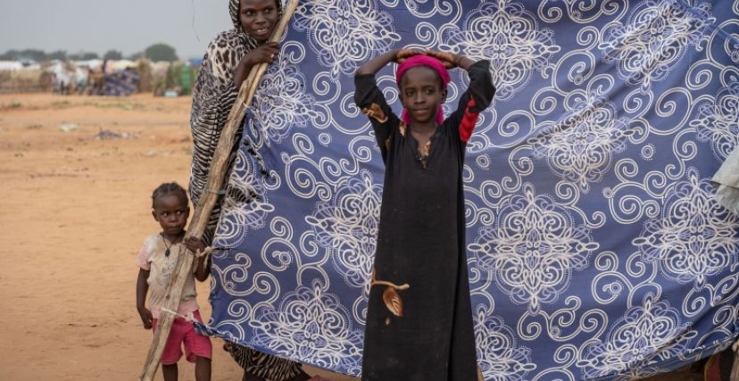 لاجئة سودانية مع طفلتها وطفلها في أحد مخيمات اللجوء