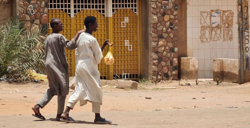 شابان يحملان بعض الرغيف في أحد شوارع الخرطوم خلال الحرب