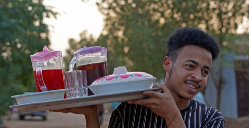 شاب بحمل صينية المشروبات الرمضانية في السودان ويظهر فيها الحلو مر 