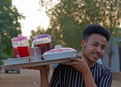 شاب بحمل صينية المشروبات الرمضانية في السودان ويظهر فيها الحلو مر 